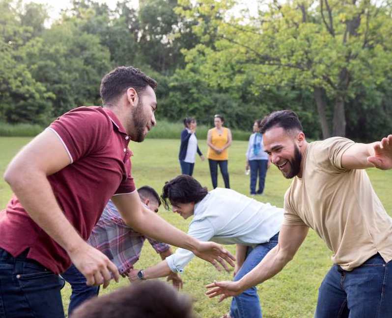 A group of ladies and men are playing together in a park some Off-Line Games